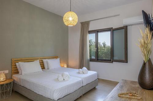 a bedroom with a bed with white sheets and a window at Mithonies Villa, with Private Pool & BBQ, By ThinkVilla in Margarítai