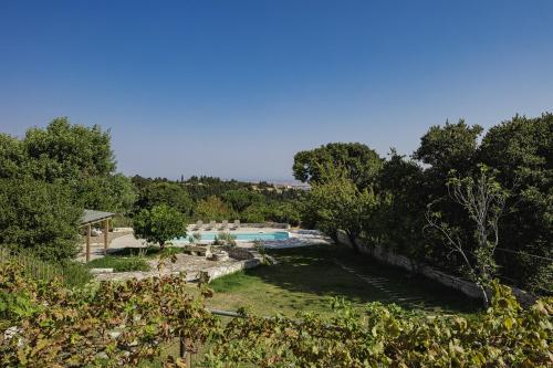 a view of a yard with a swimming pool and trees at Mithonies Villa, with Private Pool & BBQ, By ThinkVilla in Margarítai