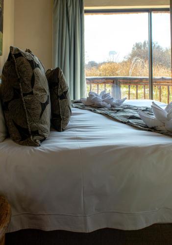 a bed with two pillows on it with a window at Tshikwalo Game Lodge in Klipdrift