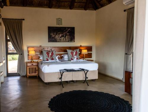 a bedroom with a large white bed with two lamps at Tshikwalo Game Lodge in Klipdrift