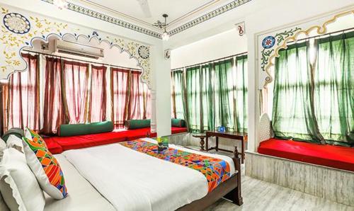 a bedroom with a bed with red and green curtains at Hotel Pichola Haveli in Udaipur