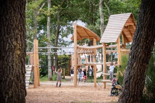 a group of children playing on a wooden playground at Village Huttopia Lac de Rillé in Rillé