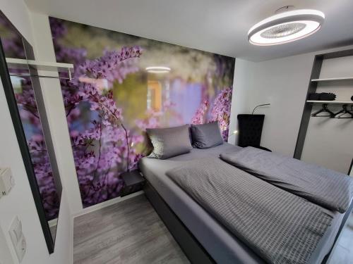 um quarto com uma cama com flores roxas na parede em Feriendomizil Apartmentschreck em Volkach