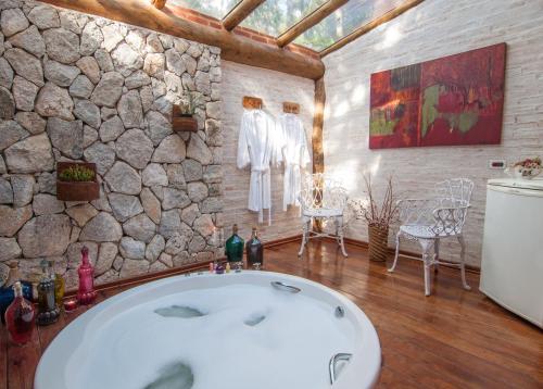 a bathroom with a large tub in a stone wall at Pousada Alto da Neblina in Monte Verde