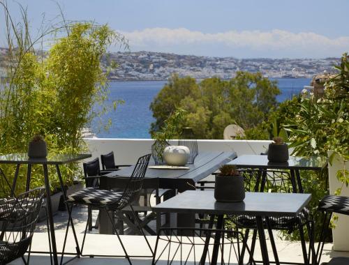 a patio with tables and chairs and a view of the water at Nimbus Mykonos in Agios Stefanos