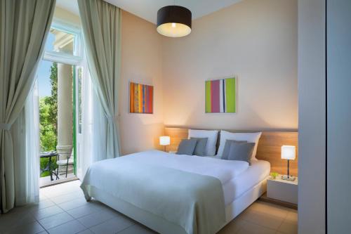 1 dormitorio con cama blanca y ventana grande en Apartments Atlanta - Liburnia, en Lovran