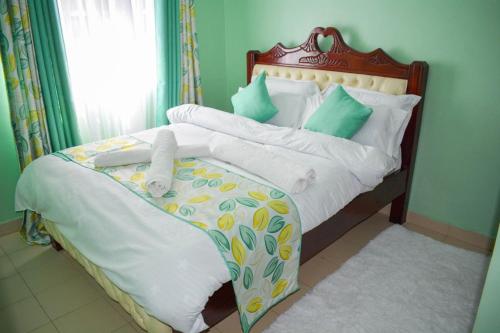 a bed with white sheets and green pillows at Fika Casa in Nakuru