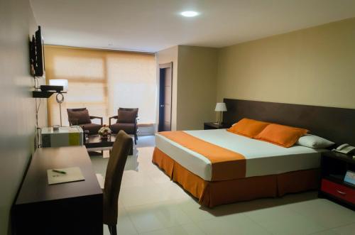 Habitación de hotel con cama, escritorio y silla en Hotel Los Almendros, en Manta