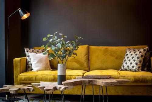a yellow couch in a living room with a table at L' Hôtel & Spa Ribeauville- Haut-Koenigsbourg in Ribeauvillé