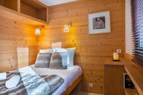 a bedroom with wooden walls and a bed with pillows at Val Thorens-Cosy Lauzières 315 in Val Thorens