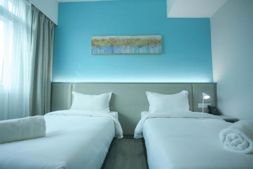 two beds sitting next to each other in a room at Stanton City Hotel in Kota Kinabalu