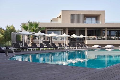 un hôtel avec une piscine dotée de chaises et de parasols dans l'établissement NEMA Design Hotel & Spa - Adults Only, à Chersónissos