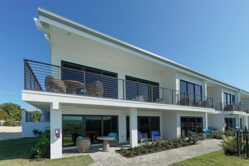 a white house with a balcony with chairs at Anna Maria Beach Resort in Holmes Beach