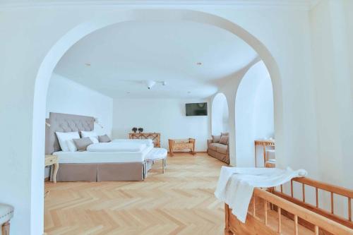 a white bedroom with a bed and a couch at Brauereigasthof zum Kuchlbauer in Abensberg