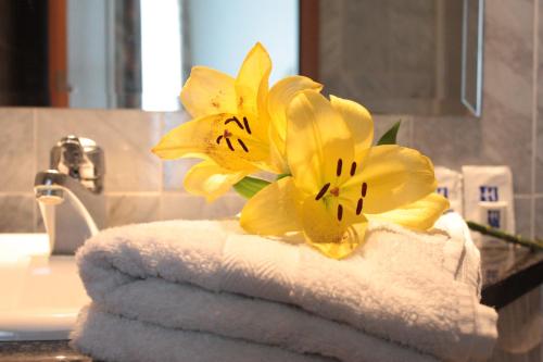 a pile of towels with yellow flowers on a sink at Hotel Mainbogen in Offenbach