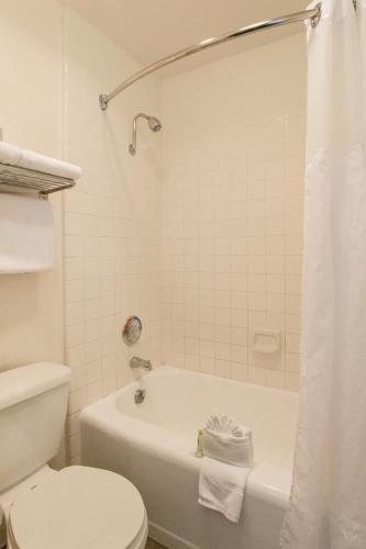 a bathroom with a white tub and a toilet at Kings Inn in San Diego
