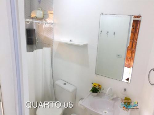 a bathroom with a toilet and a sink and a mirror at Pousada Anjos - à 2 quadras do mar in Matinhos