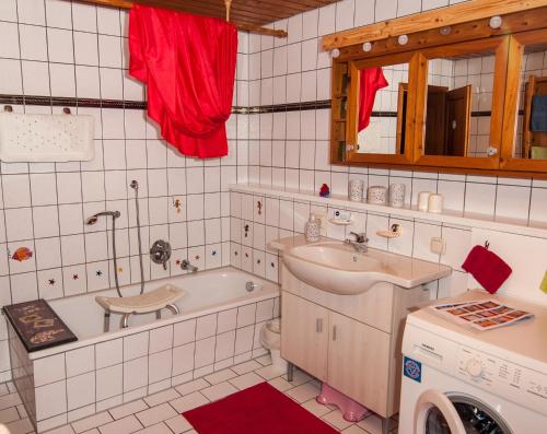 a bathroom with a tub and a sink and a washing machine at Ferienwohnung Sternschnuppe in Chieming