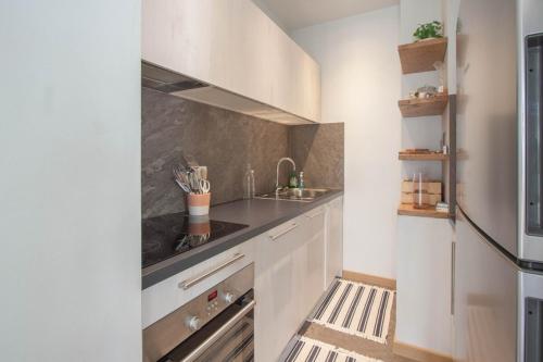 une cuisine avec des armoires blanches et un évier dans l'établissement Les Aiguilles- Town centre luxury 2 bedroom apartment, à Chamonix-Mont-Blanc