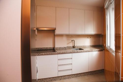 una cocina con armarios blancos y fregadero en LA CASITA DE BAUTISTA 2 llaves montanchez -caceres, en Montánchez
