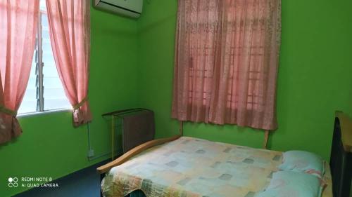 een groene slaapkamer met een bed voor een raam bij Aqil Homestay Lunas Kulim for Mslim only in Lunas