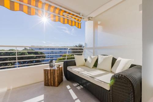 d'un balcon avec un canapé en osier et une grande fenêtre. dans l'établissement 4-Room Apartment of 96m with a Stunning View, à Cannes