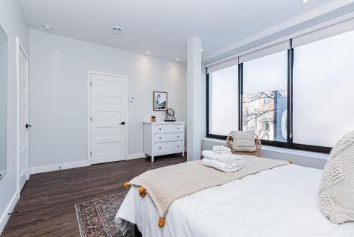 - une chambre blanche avec un grand lit et des fenêtres dans l'établissement Vast and perfectly located 3 bedroom flat by DenStays, à Montréal