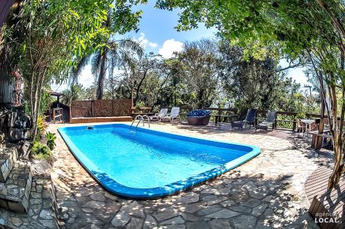 a swimming pool in a yard with a table and chairs at Pousada Rosa in Praia do Rosa