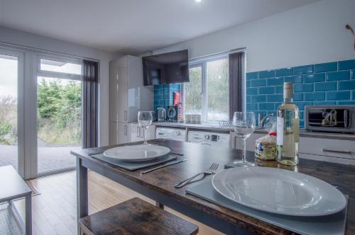 una cocina con 2 platos blancos y copas de vino en una barra en Haylands Hideaway - 1 Bedroom Apartment - Jameston en Manorbier
