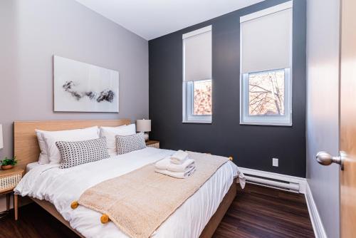 a bedroom with a bed and three windows at Family Friendly 3-bedroom beauty in Le Plateau by DenStays in Montréal