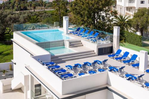 an infinity pool with blue chairs and a swimming pool at Correeira Luxury Residence in Albufeira