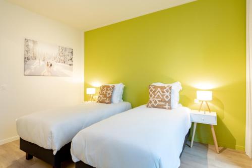 two beds in a room with a green wall at GUILLEMINS STATION FLATS in Liège