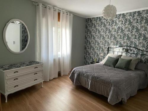 um quarto com uma cama, um espelho e uma cómoda em A casa Daló em Folgoso
