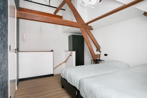 a bedroom with a white bed and wooden beams at Hello Zeeland - Appartement Weststraat 36 in Domburg