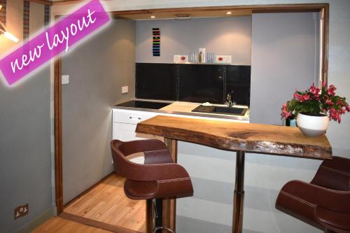 a kitchen with a counter with chairs and a table at The Retreat Tranquil Countryside Apartment in Larkhall