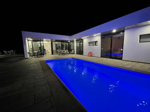 una casa con una piscina azul por la noche en Eslanzarote Eco Villa Tony, heated pool, jacuzzi, Sat tv, Super wifi, en La Costa