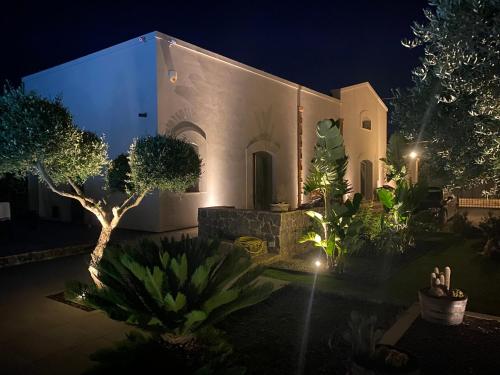 a white building with a bunch of plants at night at Signorino Suites&Pool in Marsala