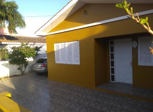 a yellow house with a car parked in front of it at Casa Yellow I Próxima a praça central in São Lourenço do Sul