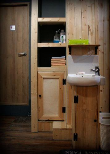 a bathroom with a sink and wooden cabinets at Gangneung Guesthouse Myu in Gangneung