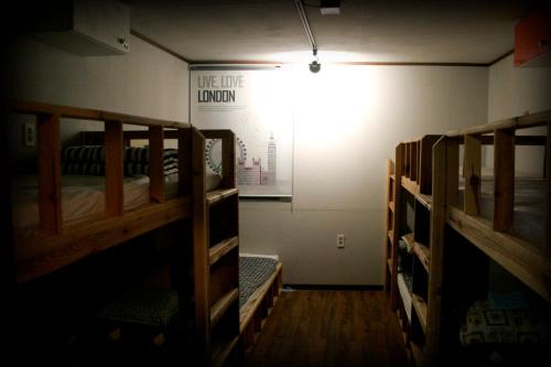 Pokój z 3 łóżkami piętrowymi i lampką na ścianie w obiekcie Gangneung Guesthouse Myu w mieście Gangneung