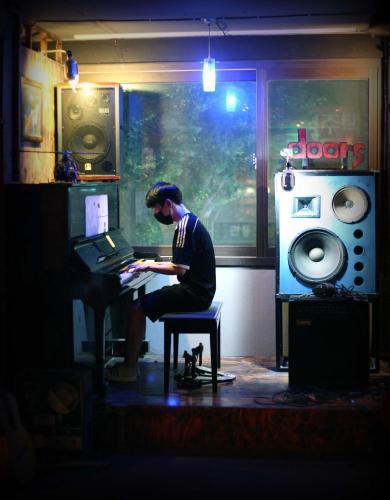 a man sitting at a piano in a room at Gangneung Guesthouse Myu in Gangneung