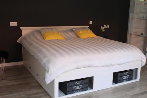 a white bed with two yellow pillows on it at Aux p'tits bonheurs la grange in Neuve-Chapelle
