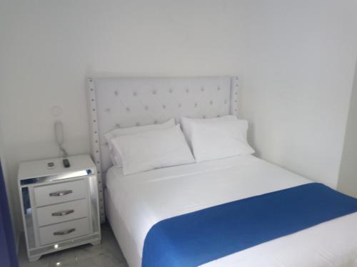 a bedroom with a white bed and a night stand at Hotel Señorial in Santo Domingo