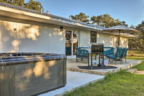 a patio with a table and chairs and an umbrella at Quiet Haven with Hot Tub, 4 Mi to Canyon Lake! in Fischer