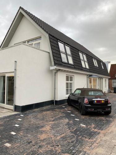 a black car parked in front of a white house at LOFT15 in Den Burg