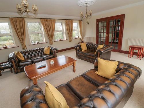 a living room with leather couches and a table at Barnacre in Morpeth