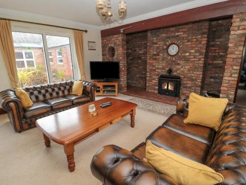 a living room with leather furniture and a fireplace at Barnacre in Morpeth