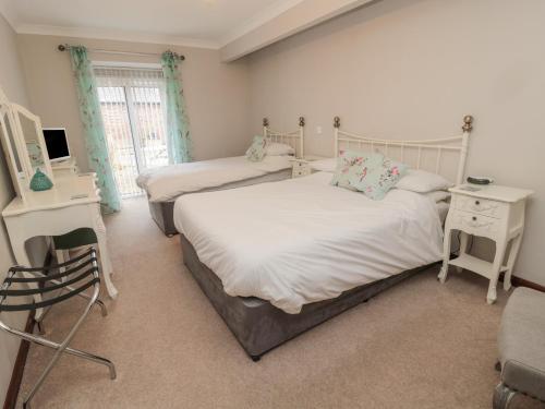 Un dormitorio con dos camas y un escritorio y una silla. en Barnacre, en Morpeth