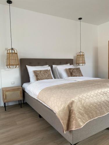 a bedroom with a large bed with two lights at LOFT15 in Den Burg