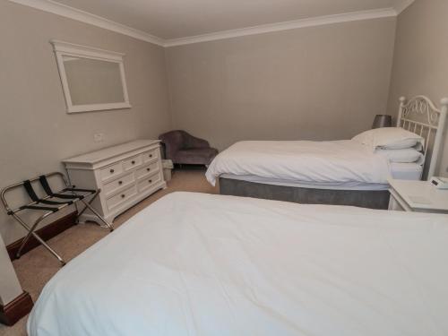 a bedroom with two beds and a chair and a dresser at Barnacre in Morpeth